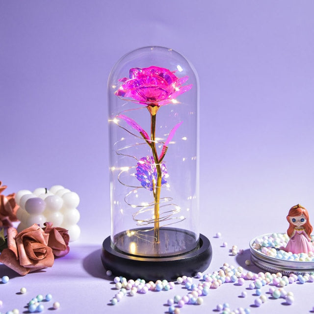 Artificial galaxy rose flowers in glass dome with LED lighting on black wood base, perfect for home decor or romantic gift for Valentine's Day, weddings. or any special occasion.