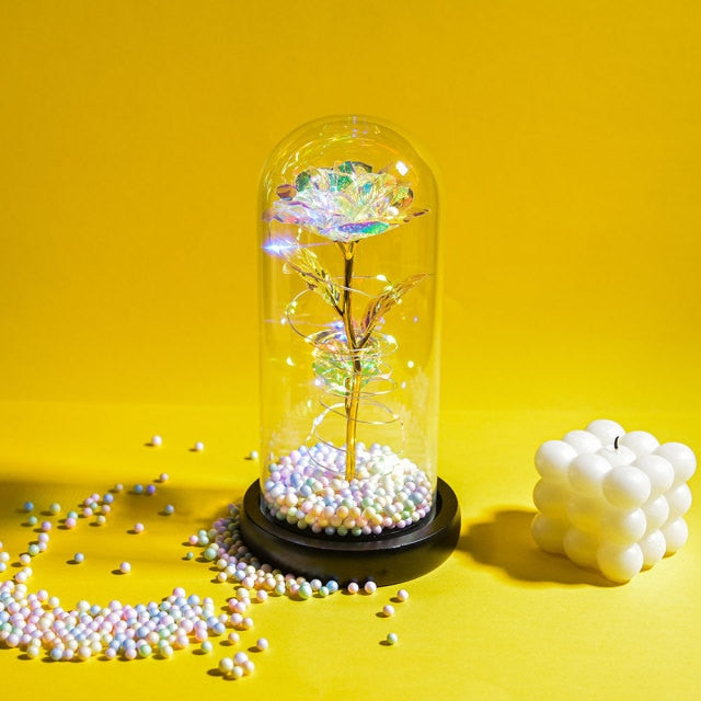 Artificial galaxy rose flowers in glass dome with LED lighting on black wood base, perfect for home decor or romantic gift for Valentine's Day, weddings. or any special occasion.