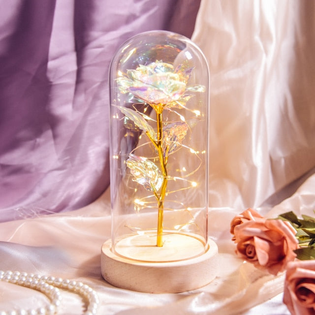 Artificial galaxy rose flowers in glass dome with LED lighting on black wood base, perfect for home decor or romantic gift for Valentine's Day, weddings. or any special occasion.