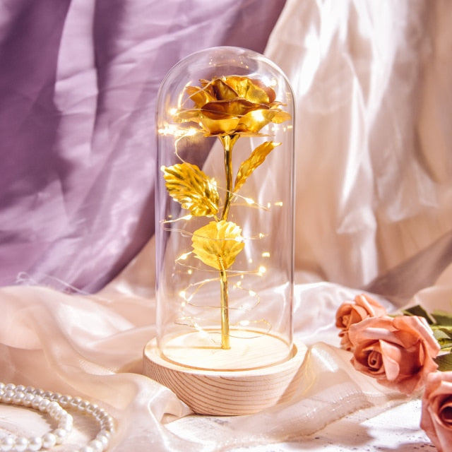 Artificial galaxy rose flowers in glass dome with LED lighting on black wood base, perfect for home decor or romantic gift for Valentine's Day, weddings. or any special occasion.